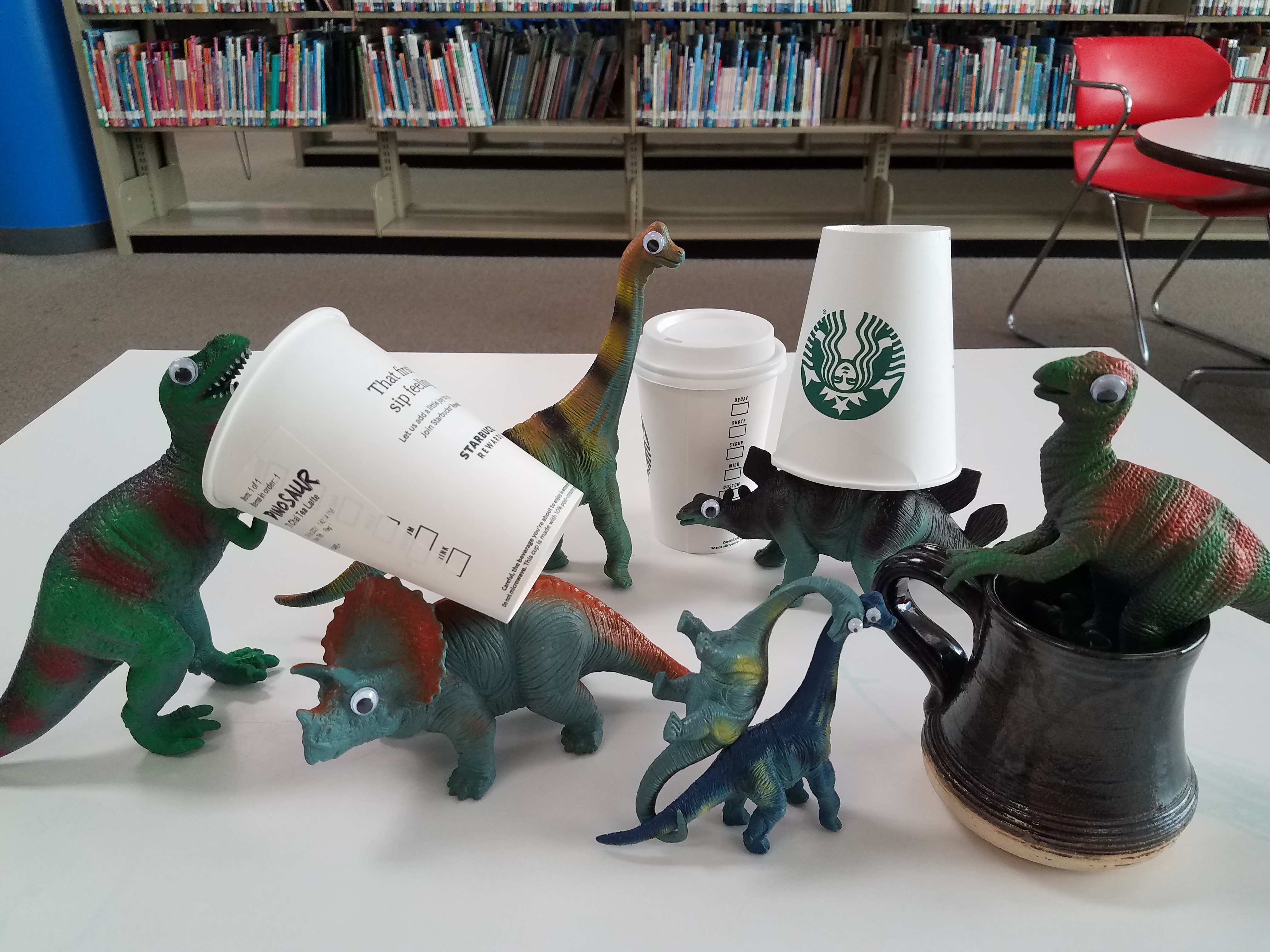 image of toy dinosaurs with googly eyes stuck on them and holding real Starbucks cups